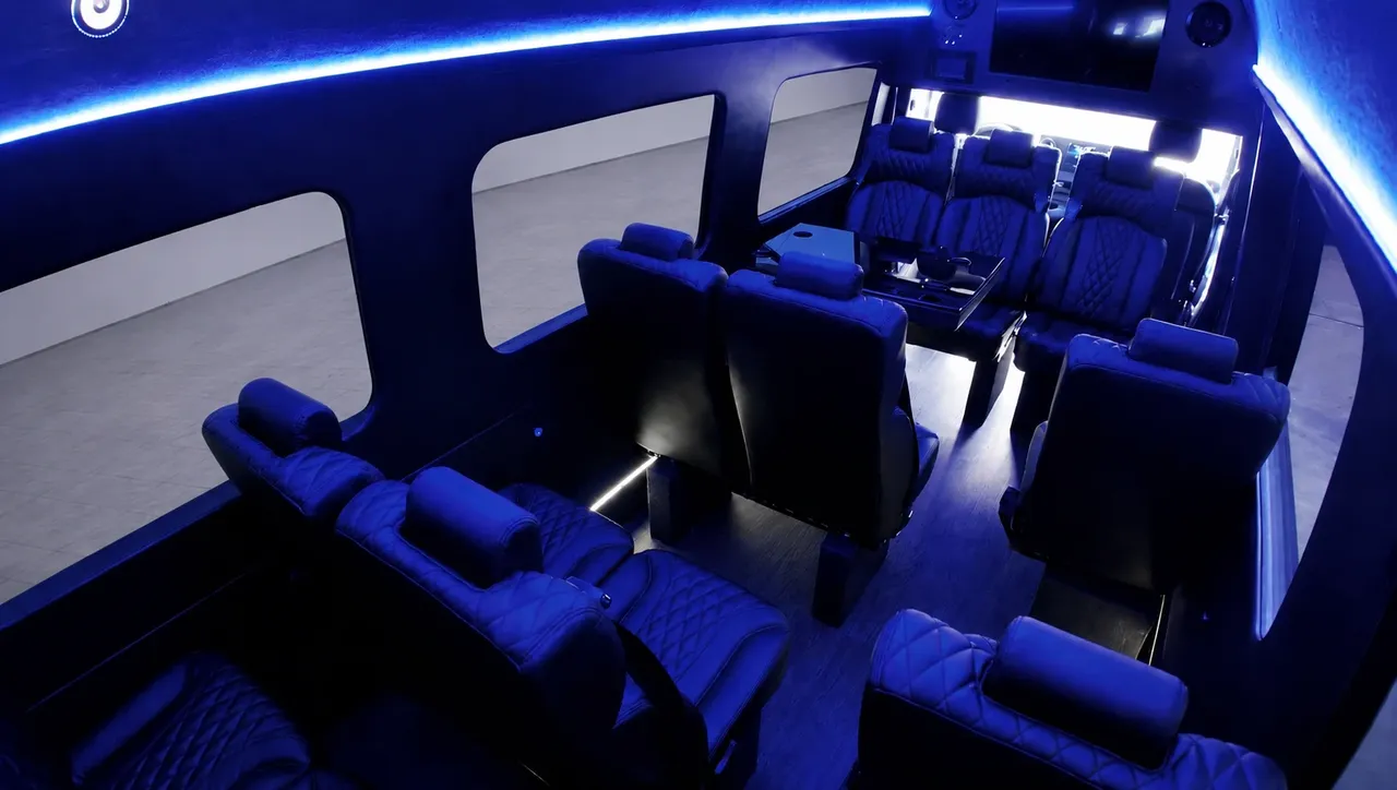 Black Luxury Sprinter Shuttle Van interior with captain's chairs, passenger tables and LED accent lighting for minibus rental