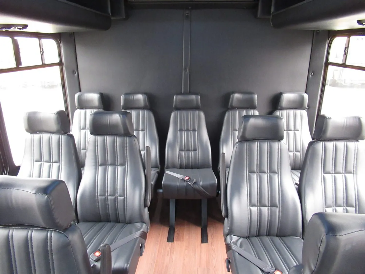 24 Passenger Ford E450 Executive VIP Shuttle Bus interior with wood-look flooring and passenger seat belts for minibus rental
