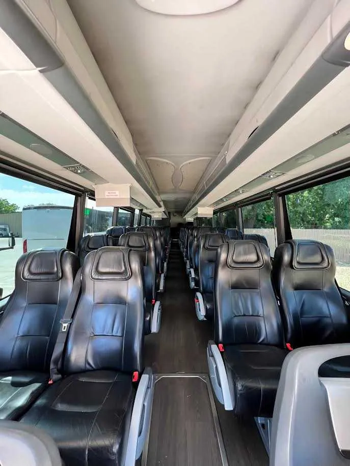 MCI Motorcoach interior with passenger seat belts and overhead parcel racks for charter bus rental in Sanders, KY