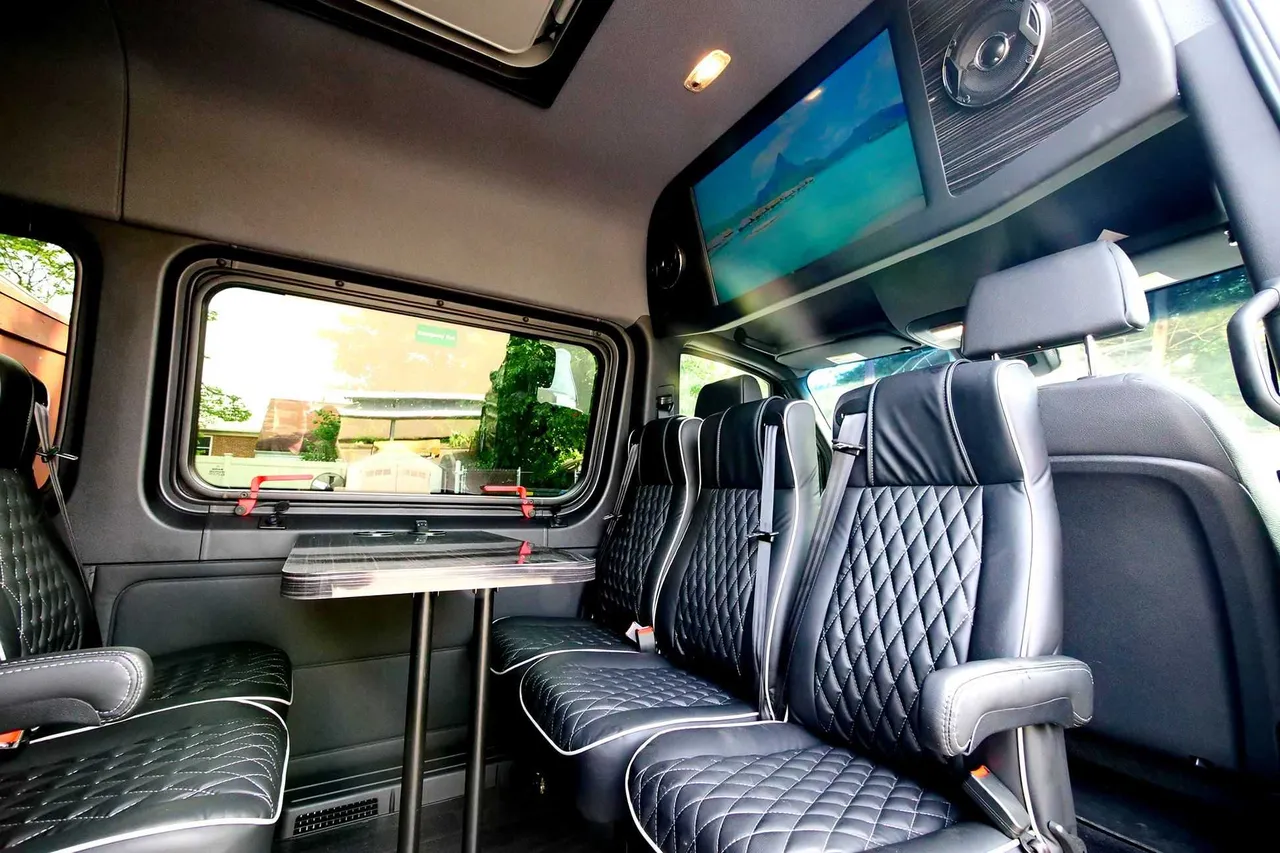 Mercedes-Benz Executive Sprinter interior with passenger tables and TV screens for minibus rental