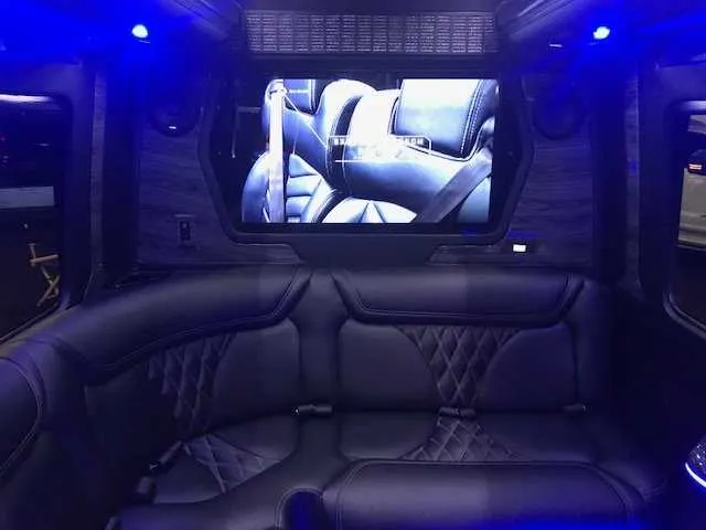 Mercedes-Benz Party Bus interior with sofa-style seating, LED accent lighting and TV screens for party bus rental