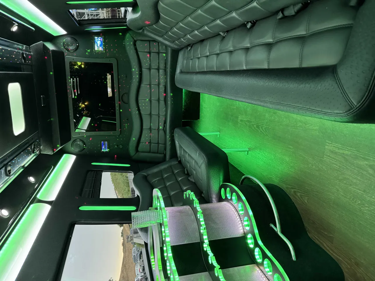 Mercedes-Benz Party Bus interior with perimeter lounge seating, LED accent lighting and wood-look flooring for party bus rental