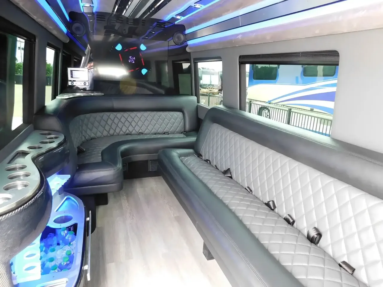 Mercedes-Benz Sprinter Limousine interior with perimeter lounge seating, LED accent lighting and wood-look flooring for party bus rental