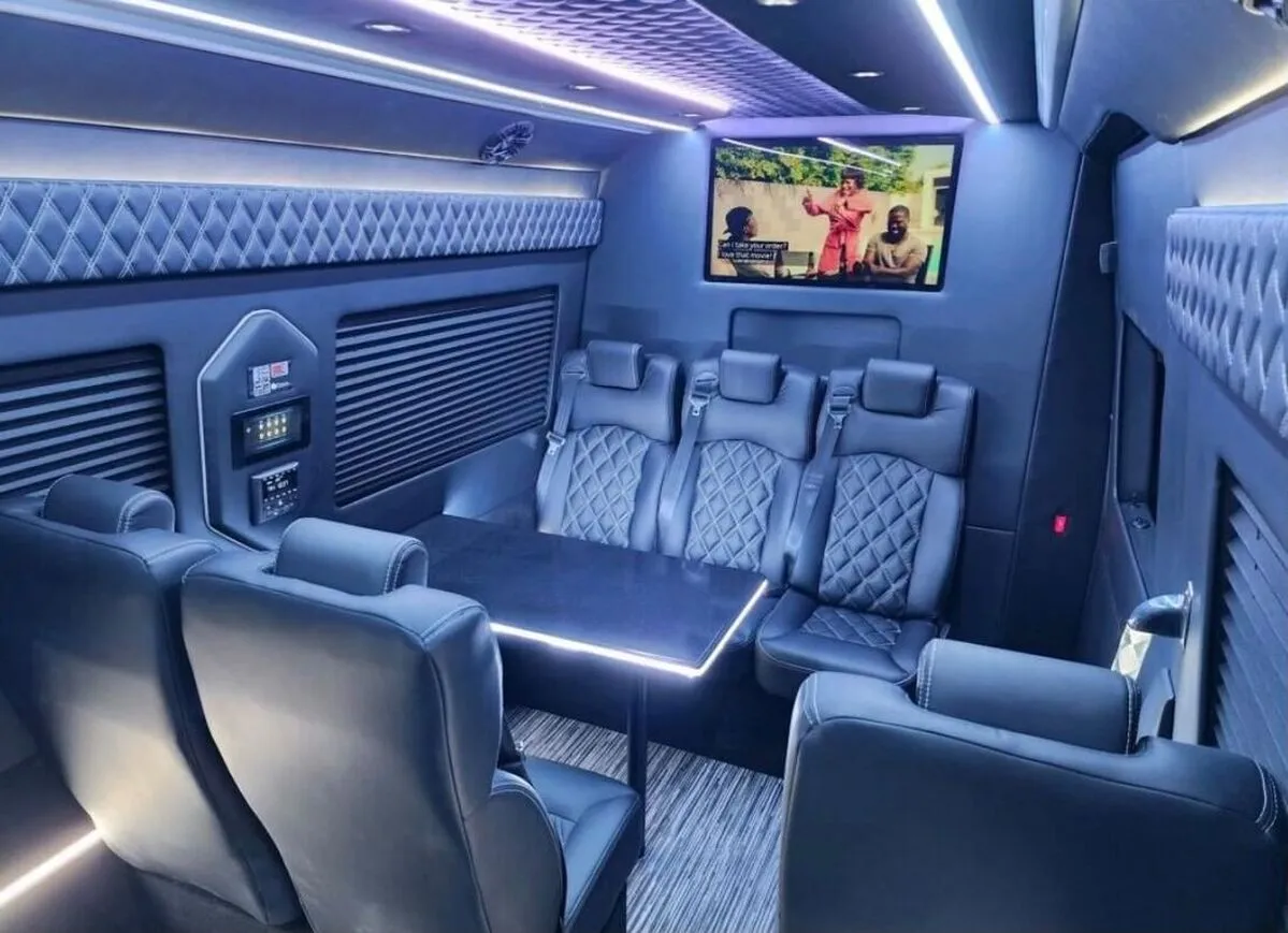 Mercedes-Benz Sprinter XL interior with captain's chairs, conference-style seating and passenger tables for minibus rental