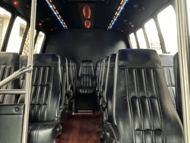 24 Passenger Mini Bus interior with LED accent lighting, wood-look flooring and grab handles and rails for minibus rental