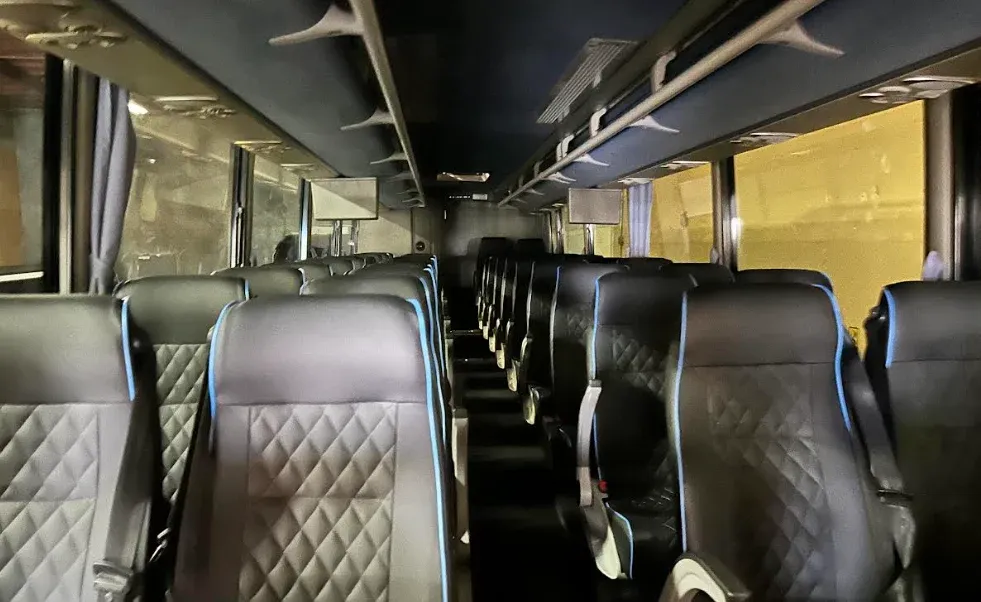 Mini Bus Mini Bus interior with airline-style seats, window shades and TV screens for minibus rental