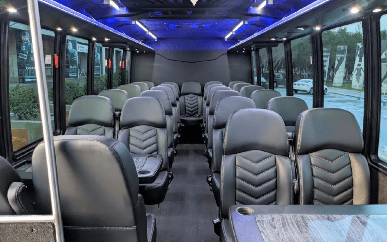 27 Passenger Mini Coach interior with passenger tables, cup holders and LED ceiling lighting for minibus rental