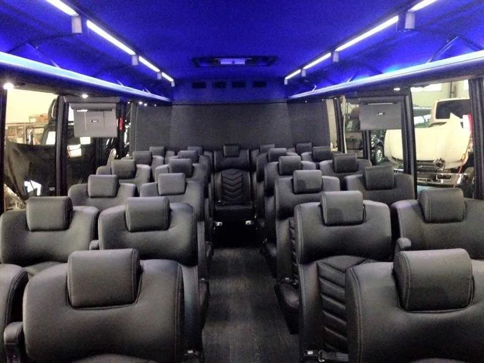 28 Passenger Mini Coach interior with airline-style seats, LED ceiling lighting and TV screens for minibus rental