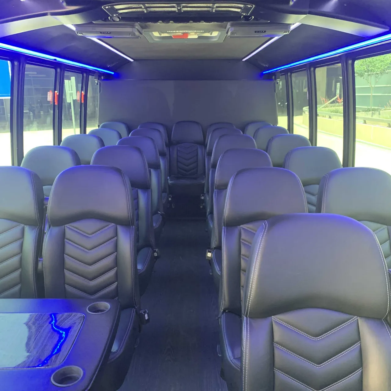 Ford F550 Executive Mini Bus interior with passenger tables, cup holders and LED accent lighting for minibus rental