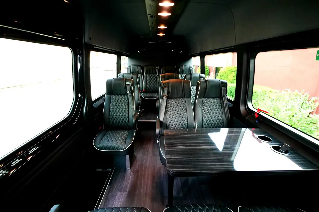 24 Passenger Mini Coach interior with captain's chairs, passenger tables and cup holders for minibus rental