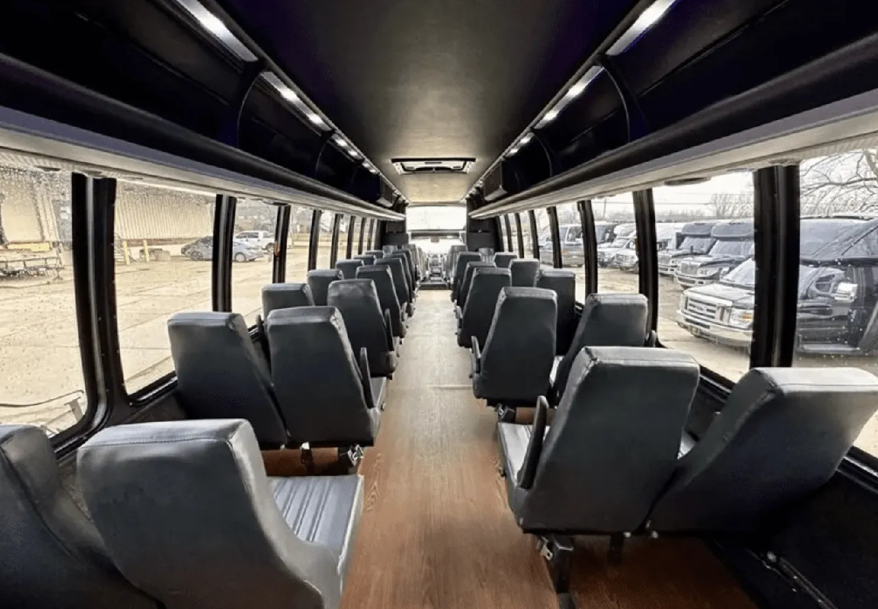30 Passenger Mini Coach interior with wood-look flooring and overhead parcel racks for minibus rental