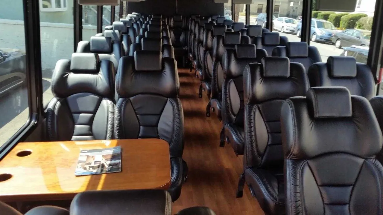 36 Passenger Mini Coach 36 Passenger Mini Coach interior with passenger tables and wood-look flooring for minibus rental