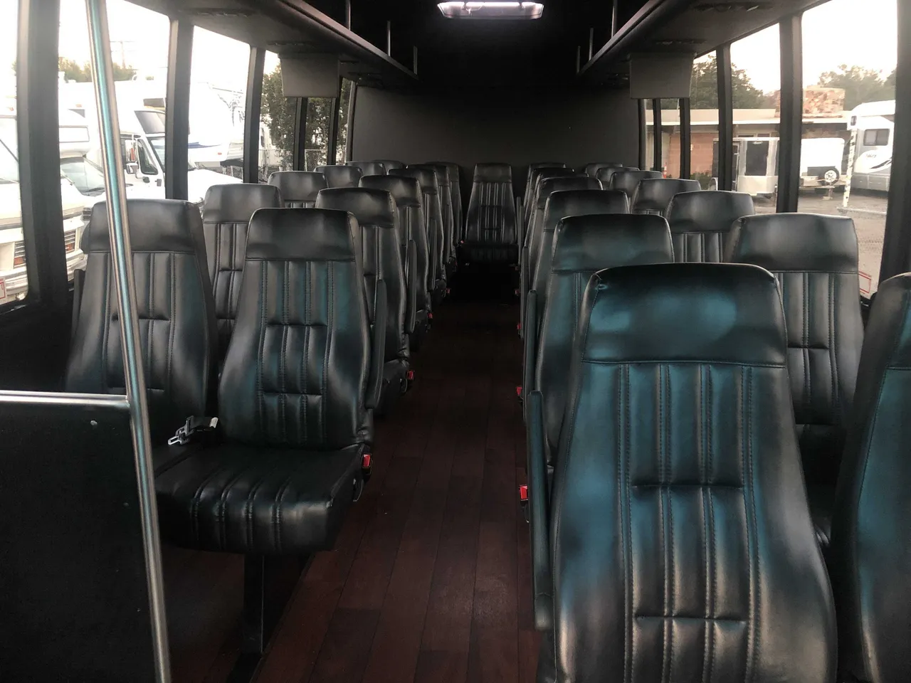 21 Passenger Mini Coach interior with airline-style seats, wood-look flooring and grab handles and rails for minibus rental