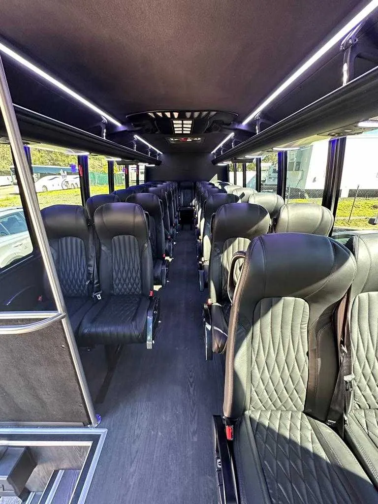 27 Passenger Minicoach interior with LED ceiling lighting, passenger seat belts and overhead parcel racks for minibus rental