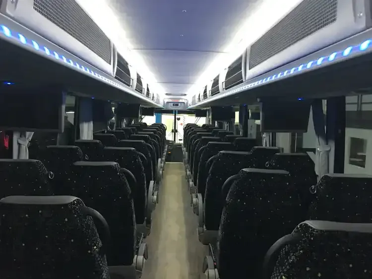 56 Passenger Motorcoach interior with LED accent lighting, LED ceiling lighting and overhead parcel racks for charter bus rental