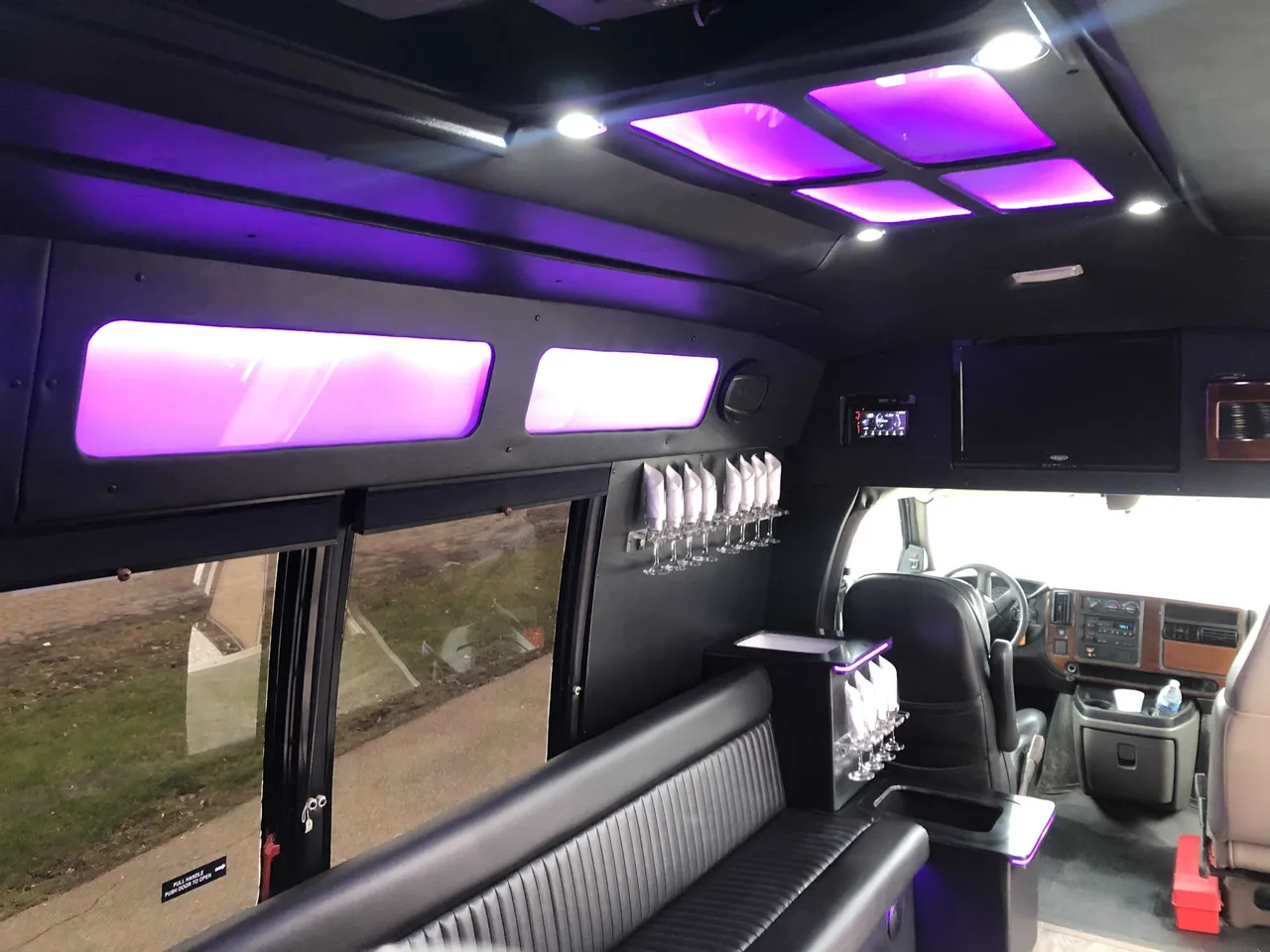 Small Party Bus interior with perimeter lounge seating, LED ceiling lighting and glassware holders for party bus rental