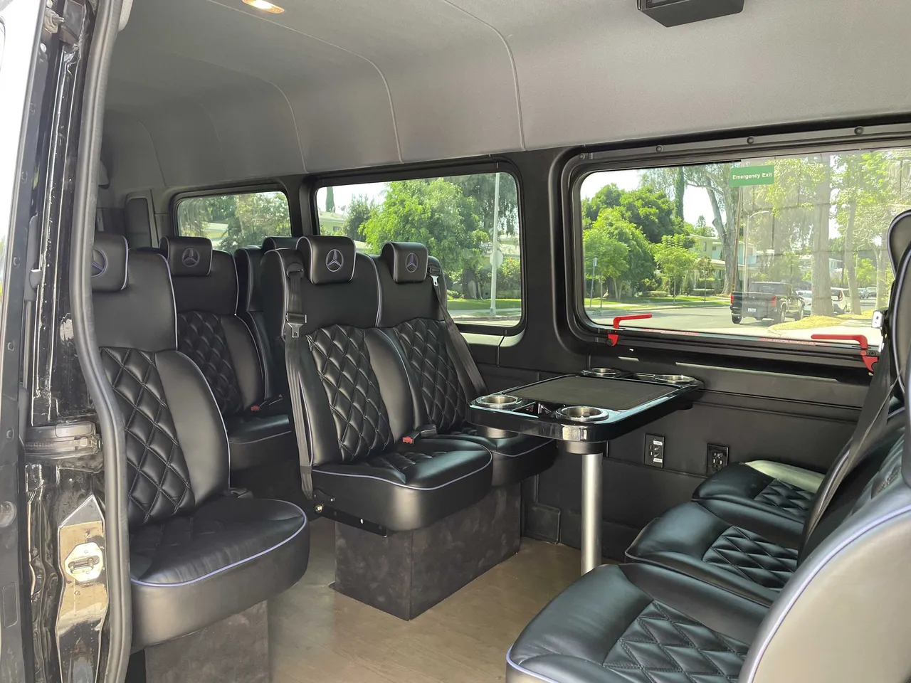 Sprinter Van interior with captain's chairs, conference-style seating and passenger tables for minibus rental